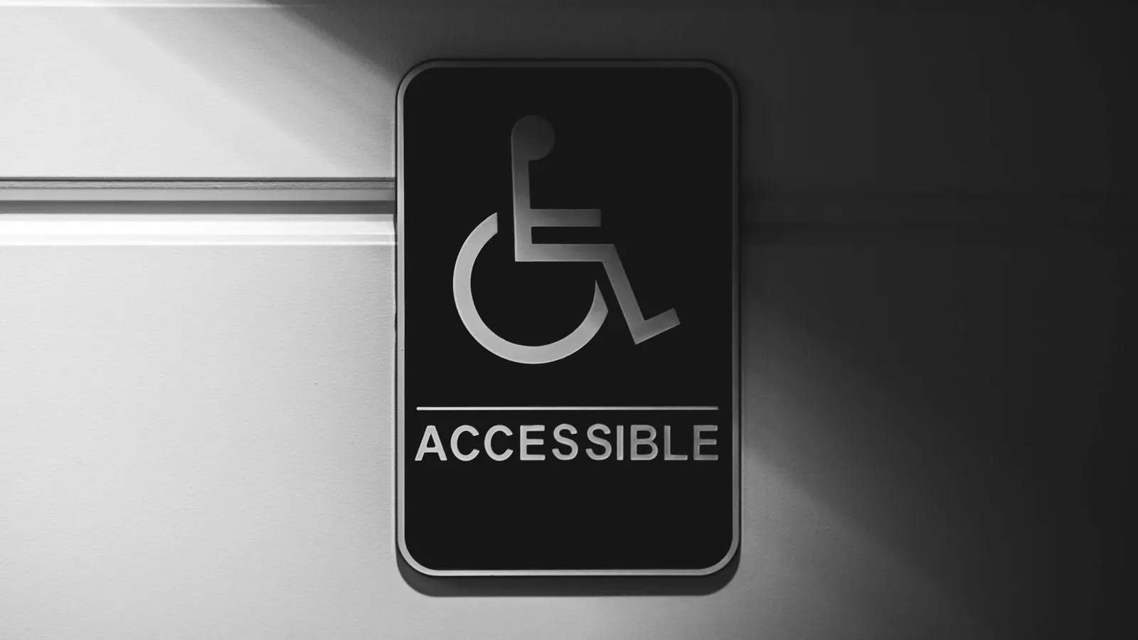 A metal sign showing the wheelchair symbol and the word Accessible.